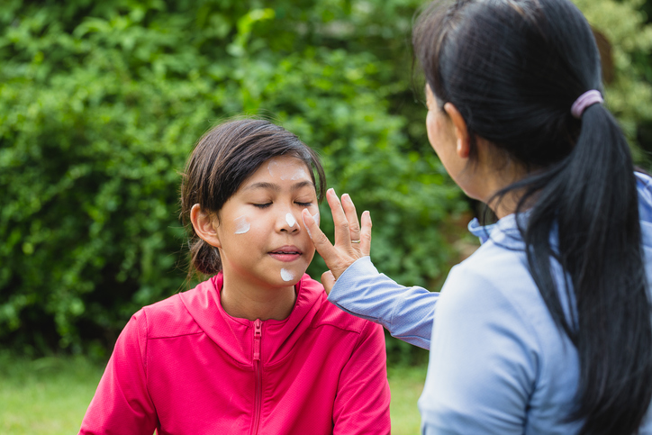 Mother applying sunscreen to her daughter's face