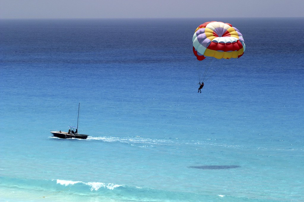 A person Parasailing and crystal clear water.