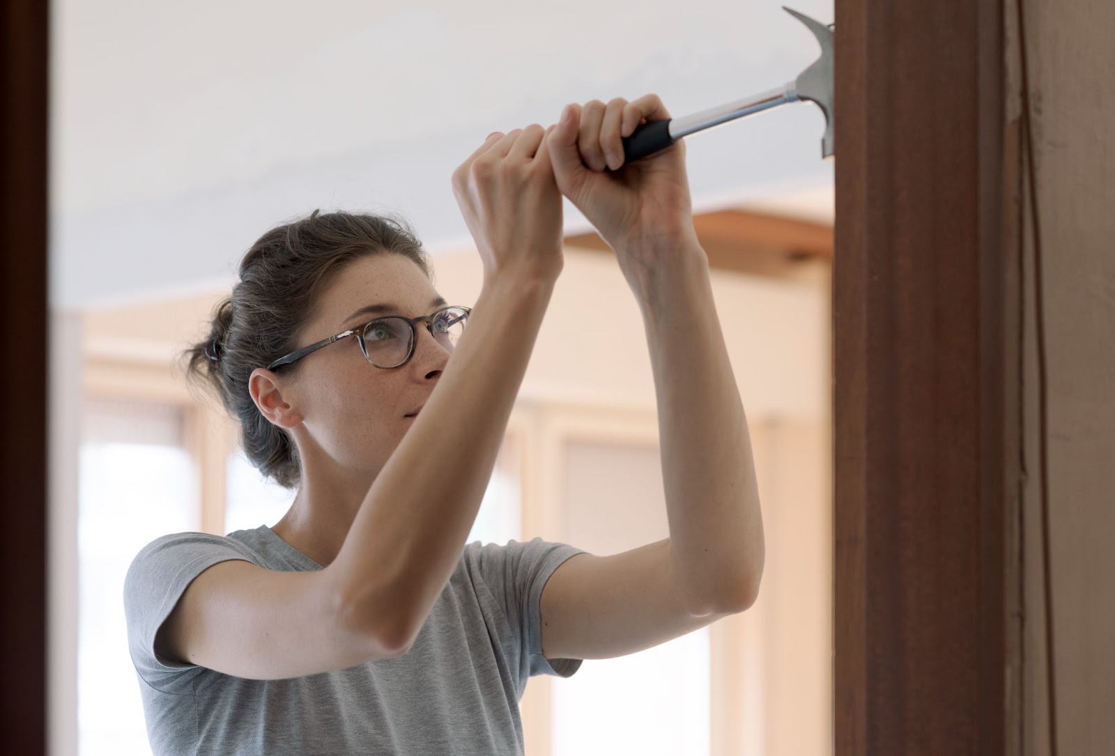 A woman holding a hammer works on installing a door.