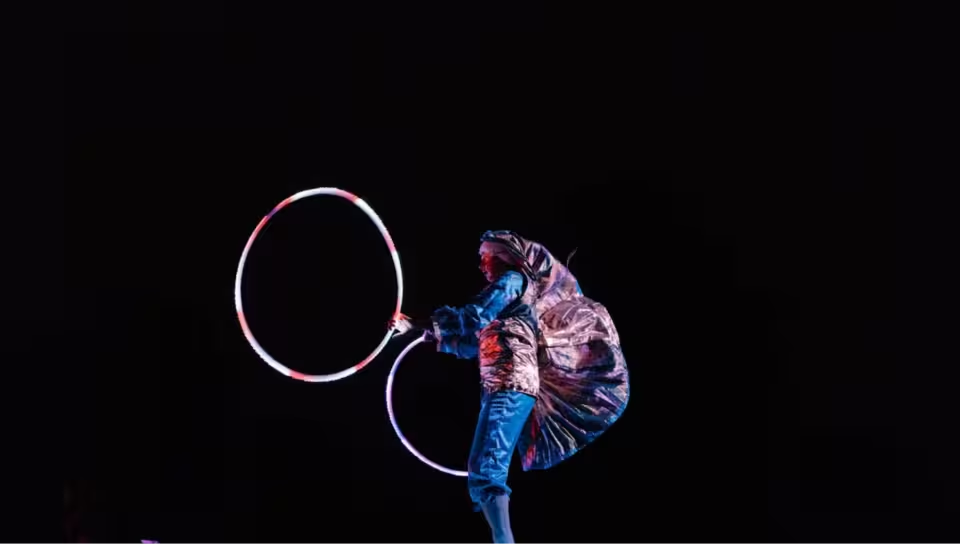 Circus performer juggles hoops in the dark