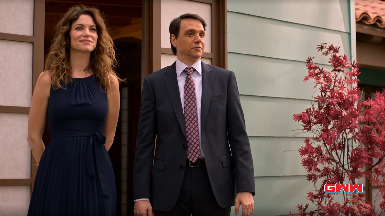 Amanda in a blue dress and Daniel in a suit standing outside.