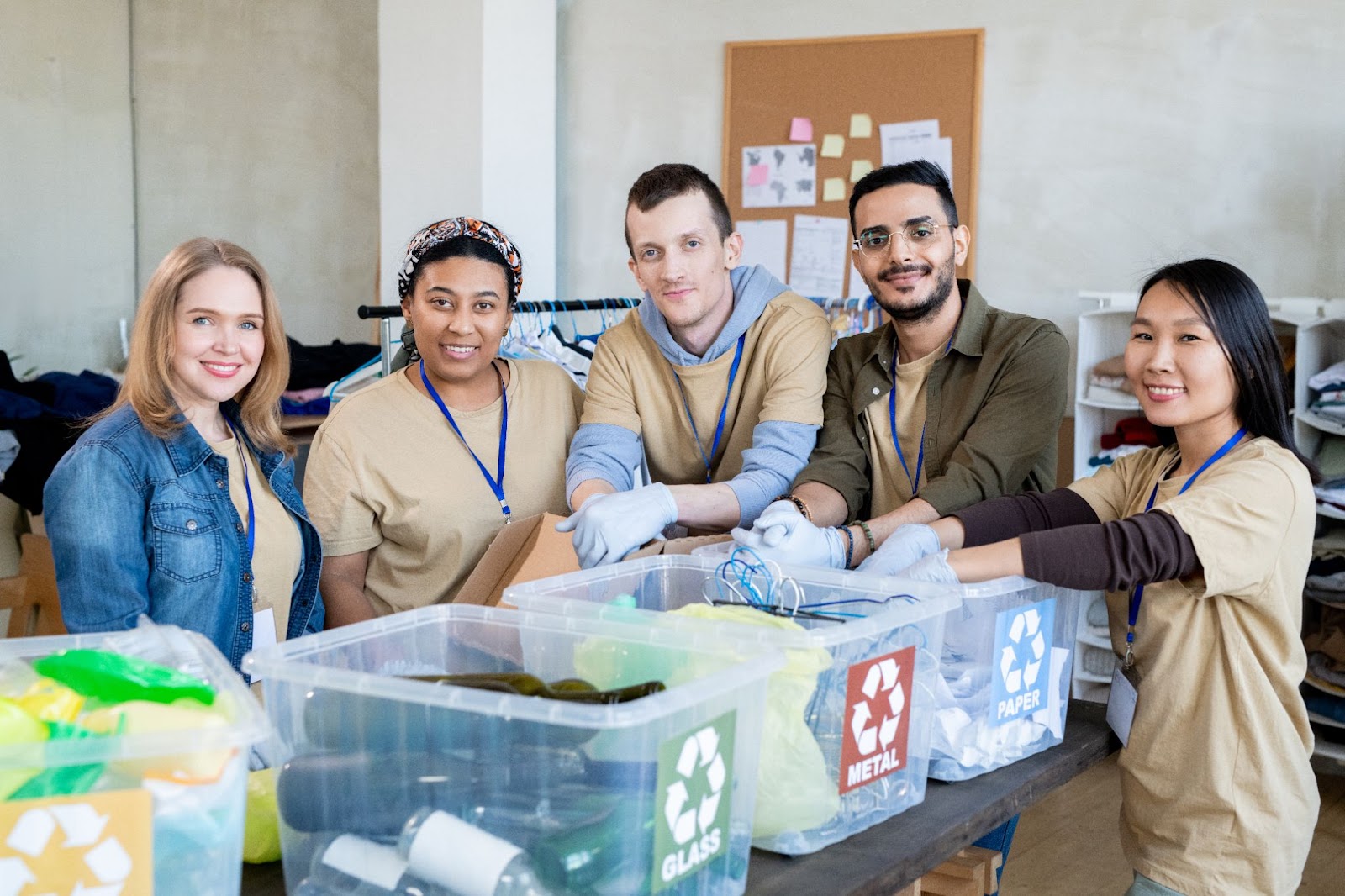  A group of workers sort through three bins of recyclable waste materials.
