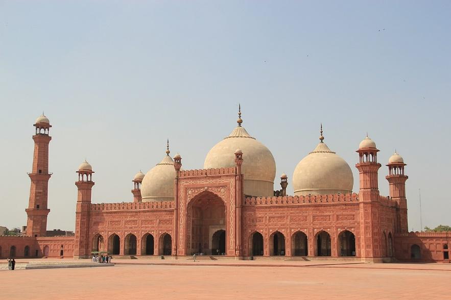 A large building with domes with Badshahi Mosque in the background

Description automatically generated