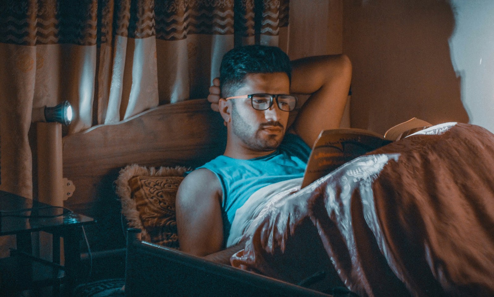 Man reading a book in bed, cozy and relaxed.