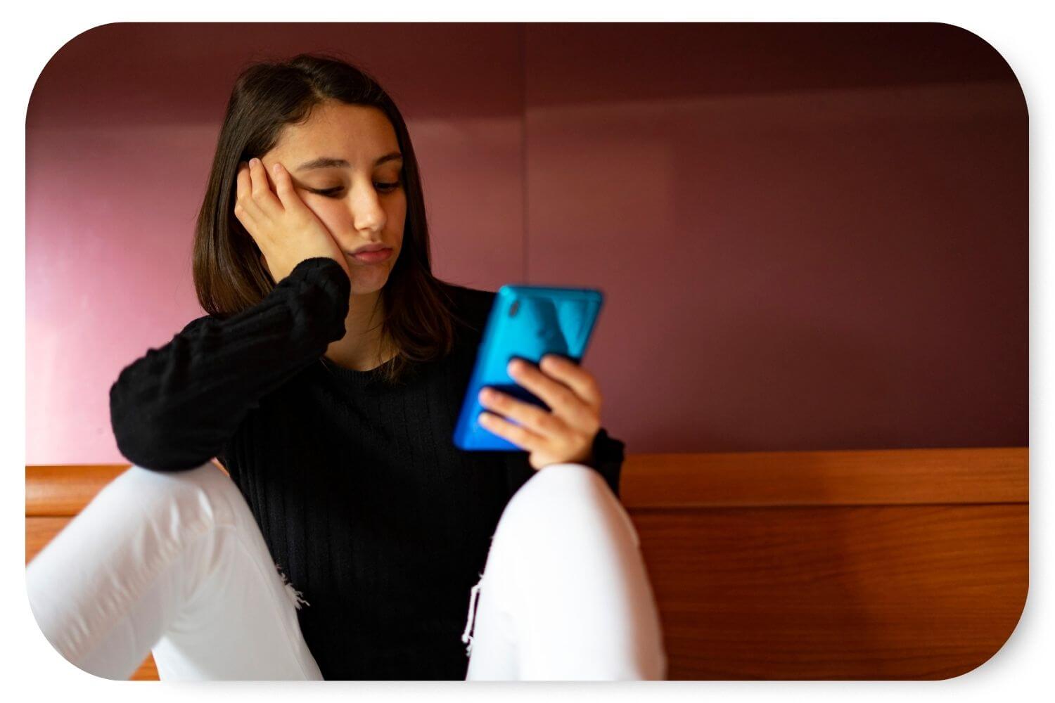 Woman looking disappointed while scrolling through social media on her phone