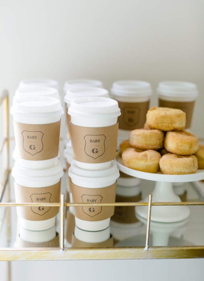 coffee cups with baby g beside a stack of donuts