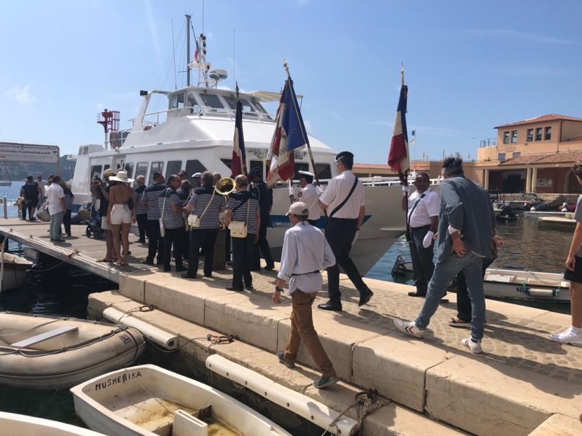 A group of people standing on a dock with flags

Description automatically generated