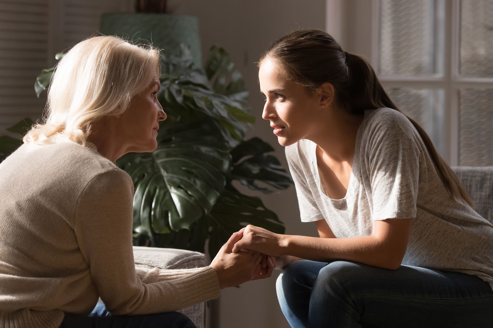 A young woman holding hands with her mother while discussing memory care.