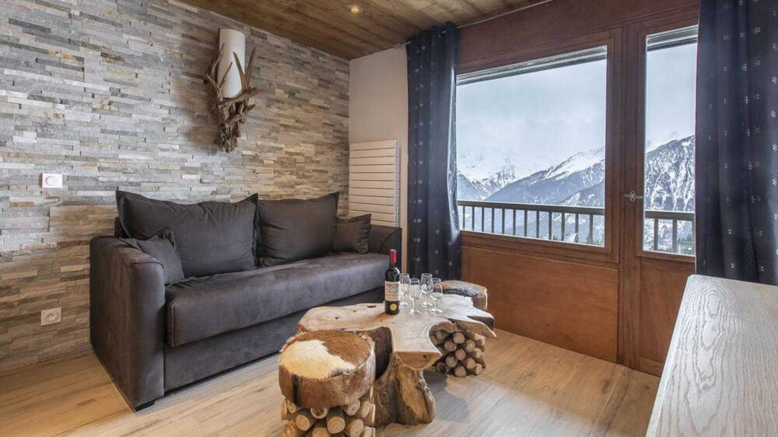 A living area with a couch and a center table with views of the French Alps. | Photo credit: Pet-Friendly Apartment in Le Praz 