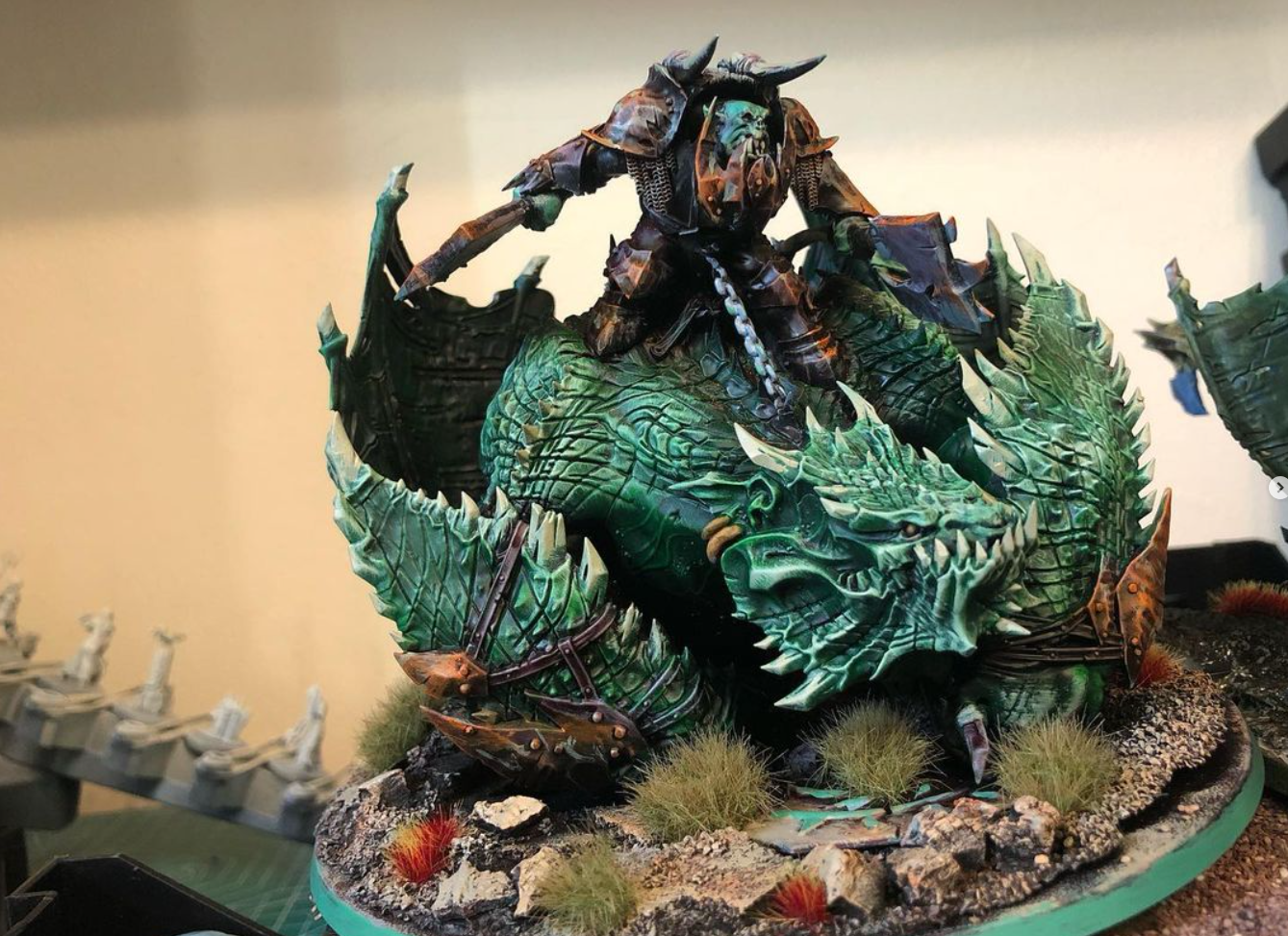 A green statue of a person riding a dragon Description automatically generated