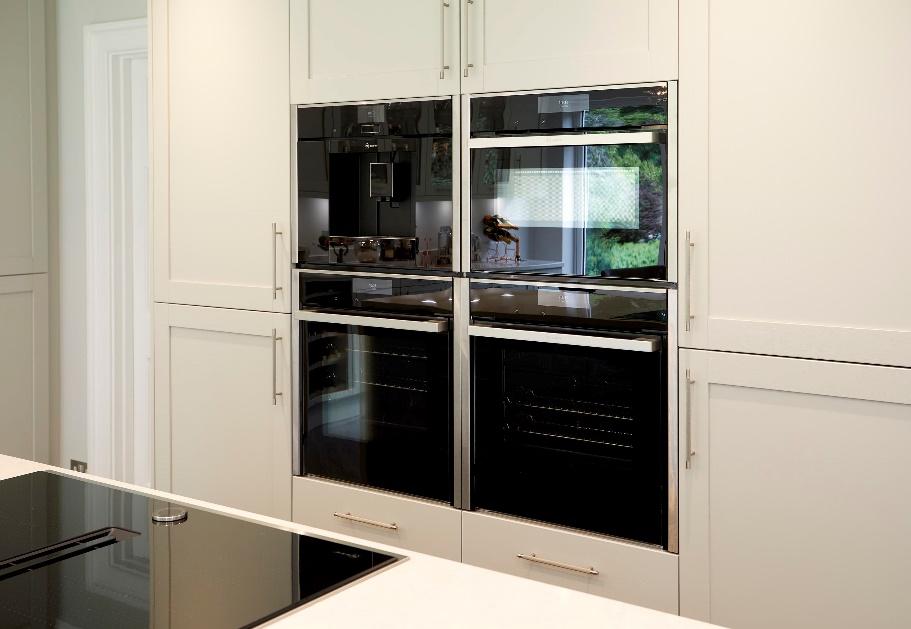A kitchen with white cabinets and black ovens

Description automatically generated