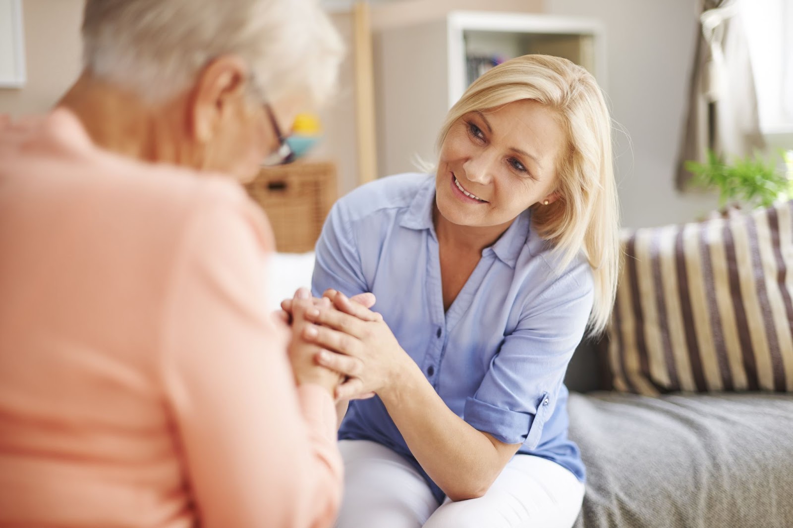 A senior woman and her daughter smiling while talking about a move to senior living.