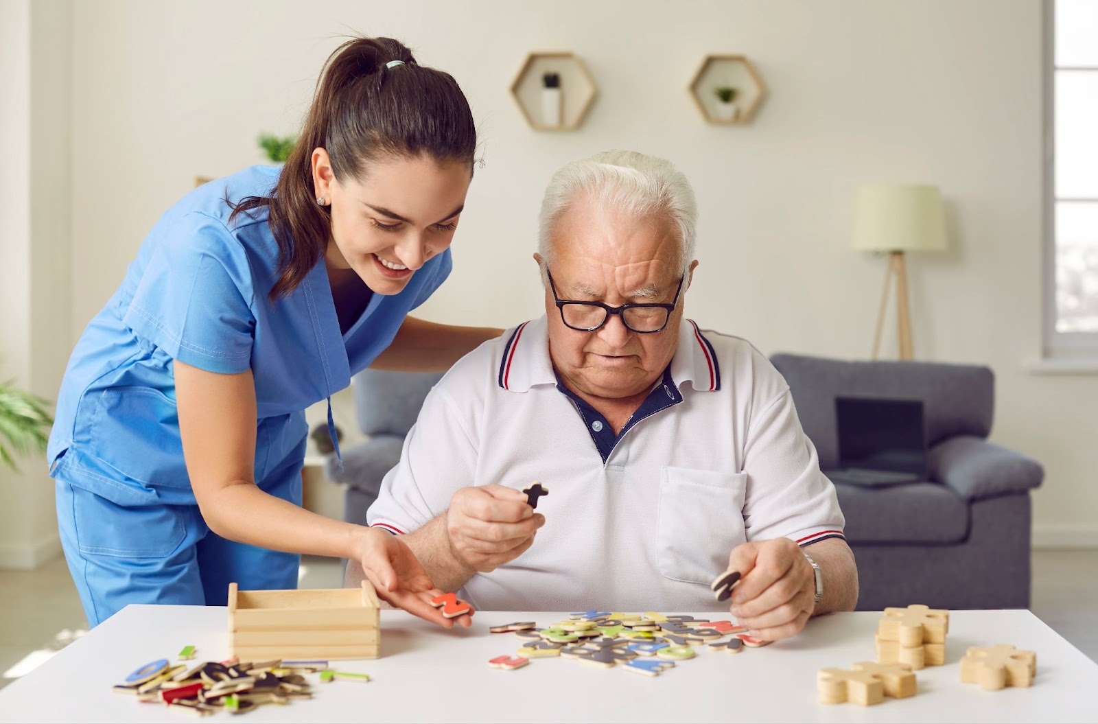 A senior man and a young caregiver in memory care working together on a letter puzzle.
