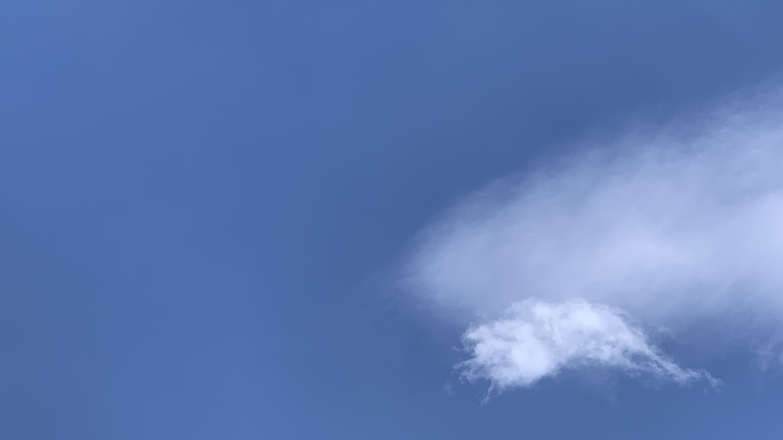 A smudgy cloud behind a little wispy cloud against lots of blue sky