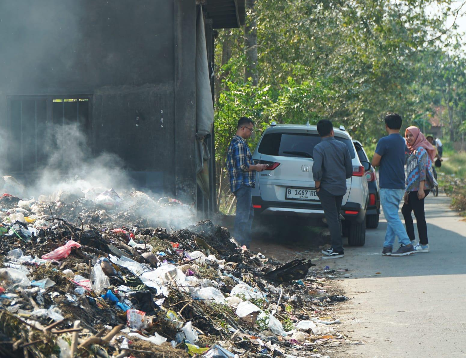 A group of people standing around a pile of garbage

Description automatically generated