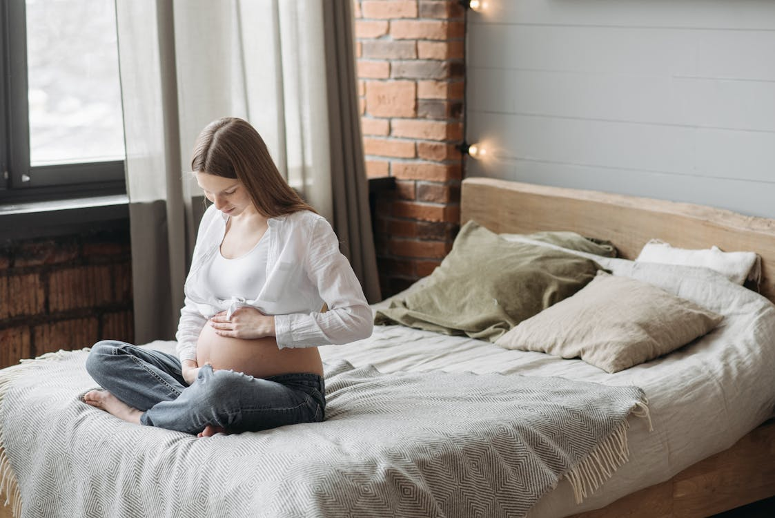 a pregnant woman sitting on a bed