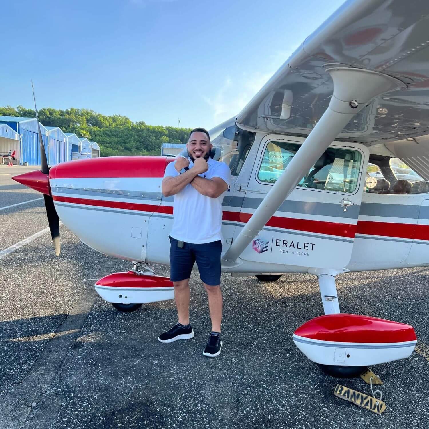 Byron crossing his arms in front of a small airplane