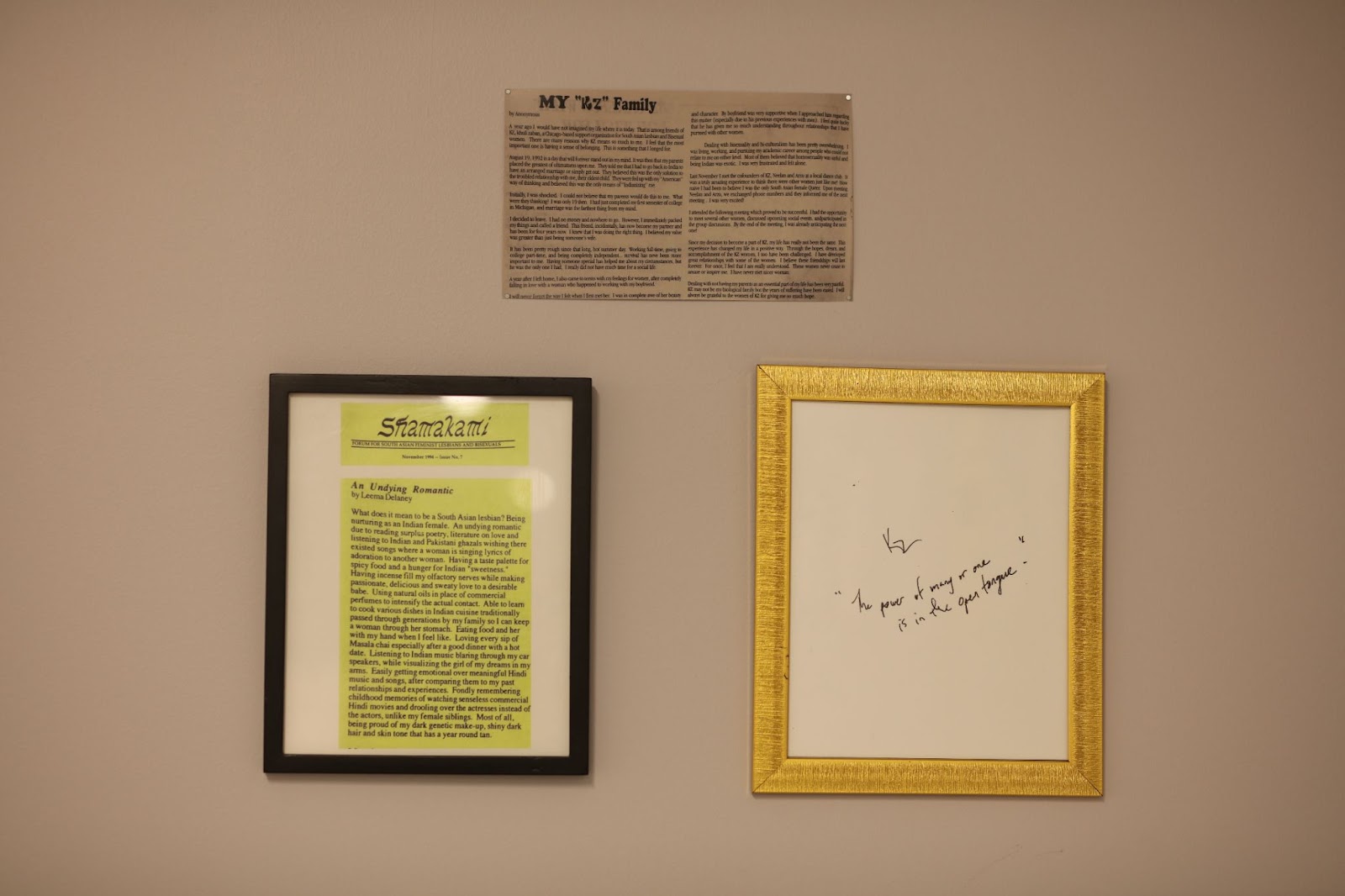 Image: Installation view, People Who Came Before Us. One unframed news clipping of an anonymous writer chronicling her experience with Khuli Zaban after being ostracized by her family in India, one excerpt from Shamakami about being a South Asian lesbian on yellow paper in a black frame, and one scrap of messy handwriting in a gold frame. Courtesy of South Asia Institute.