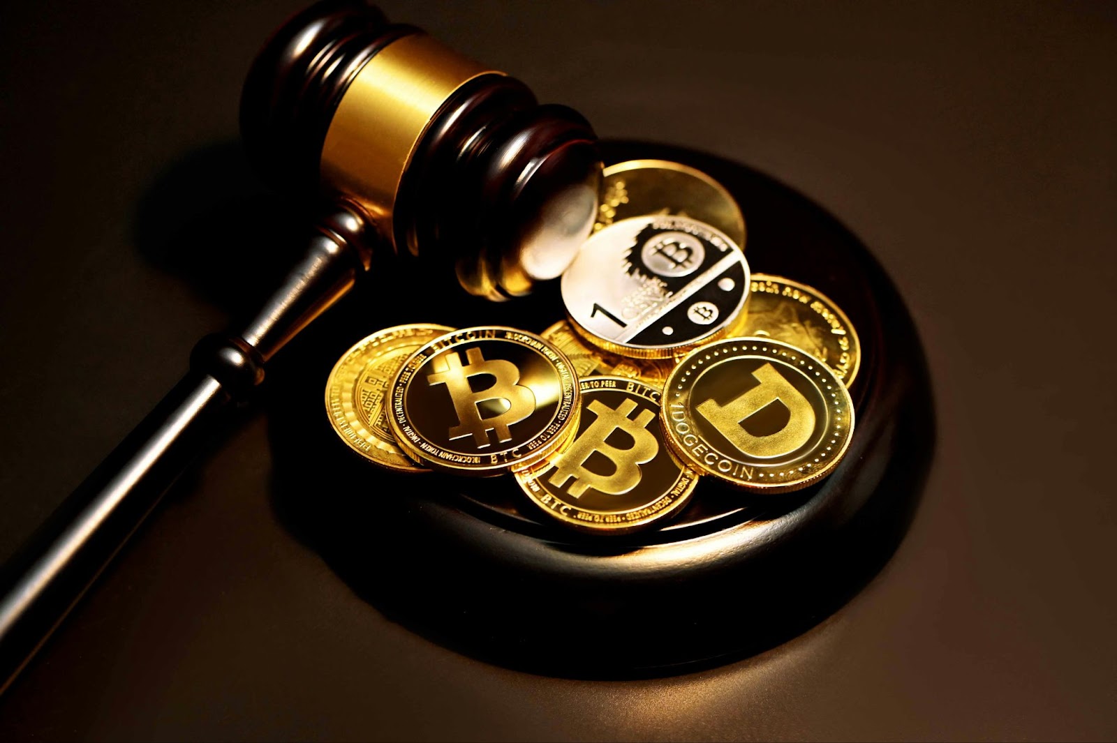 a judge's gavel resting beside a collection of gold-colored crypto scams