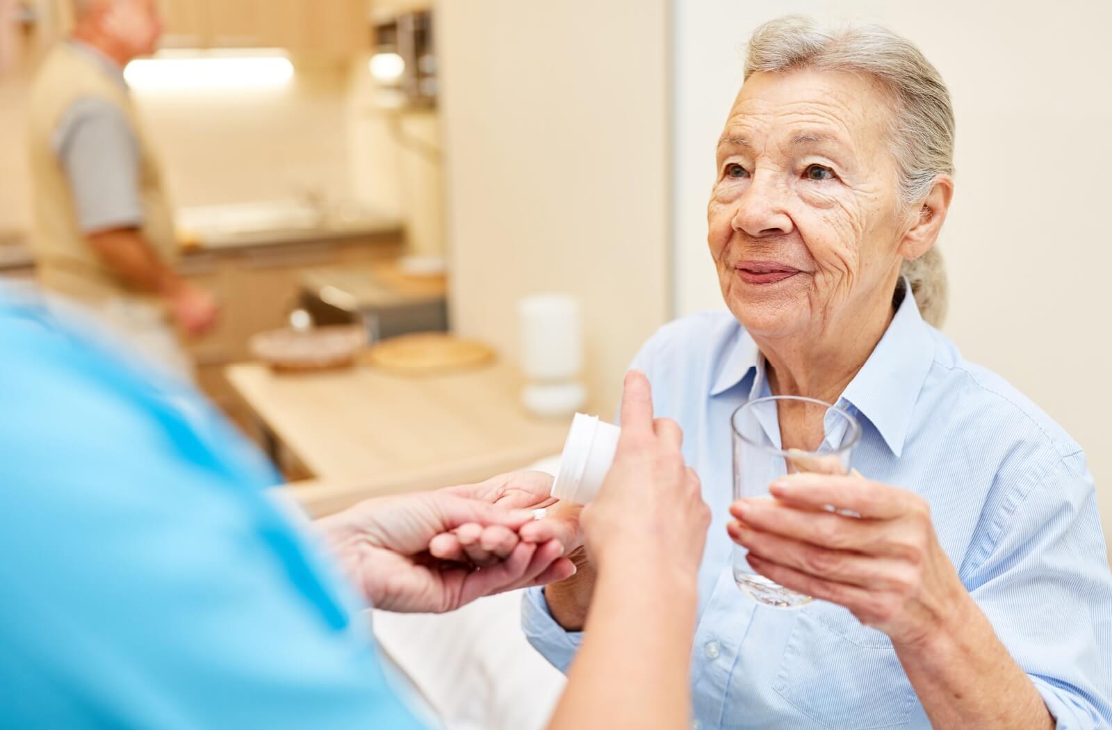 An assisted living staff member helping a resident with her medication.