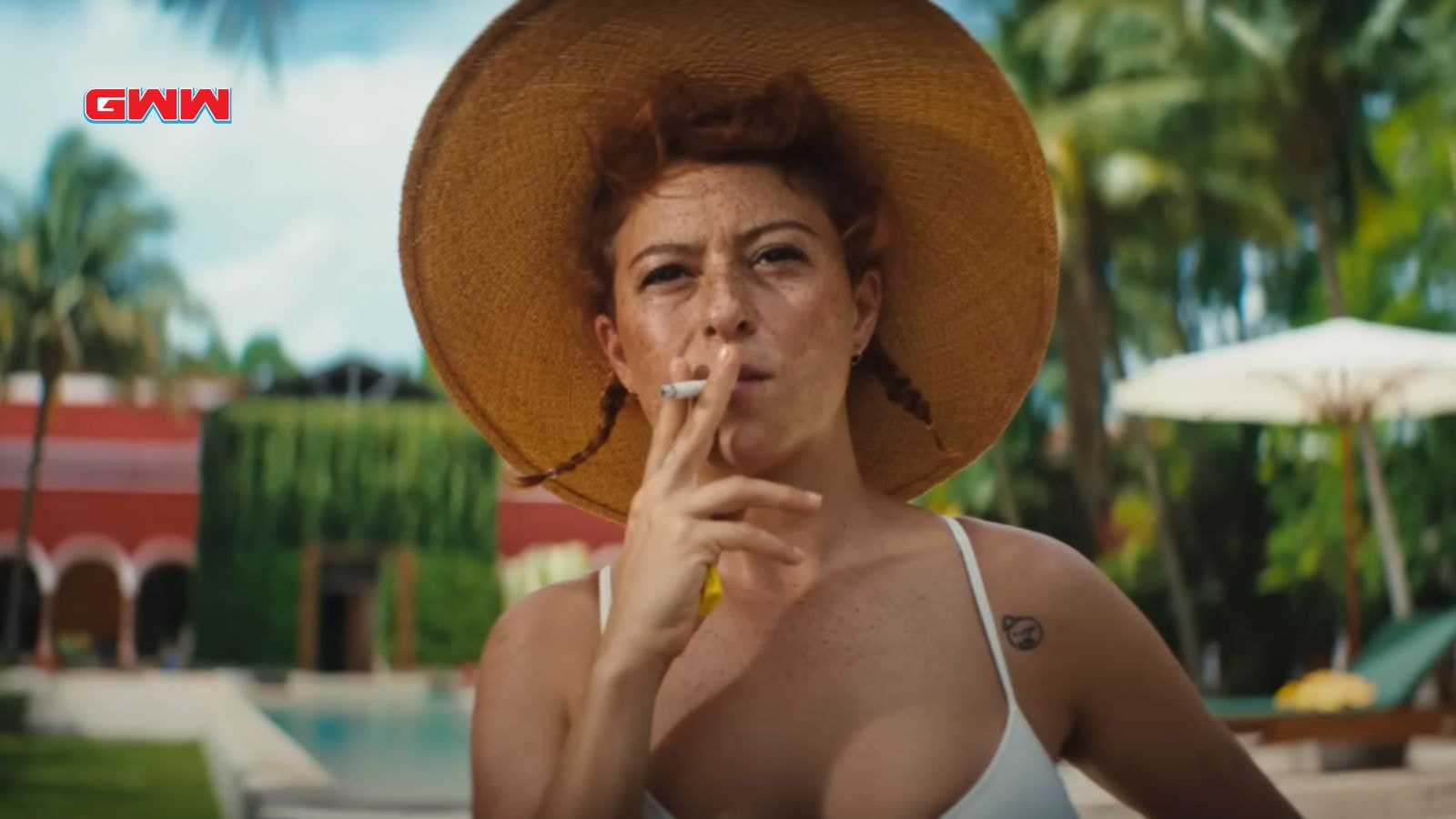 Jess in straw hat smoking by the pool.