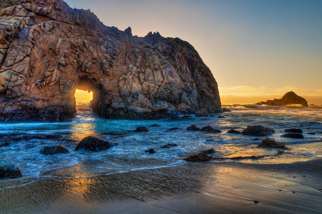 Sunset through a keyhole and rocks along the shore at one of the best beaches in the US.
