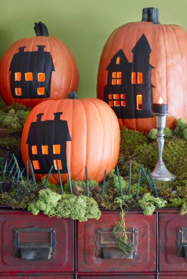 pumpkin carving ideas, pumpkins grouped together with painted black houses on the front