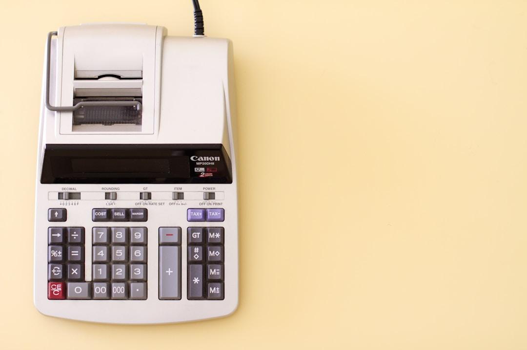 A calculator used for project accounting resting on a pale yellow background.