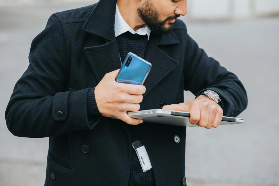 Close-up of a real estate professional checking the time on a wristwatch while holding a tablet and smartphone, highlighting the importance of time management for busy professionals.