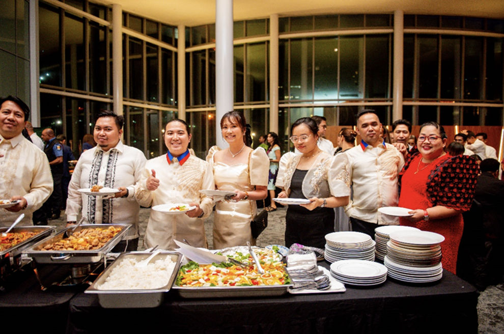 A group of people standing in front of a buffet tableDescription automatically generated