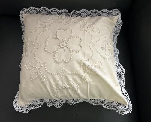 A white pillow with lace trim

Description automatically generated