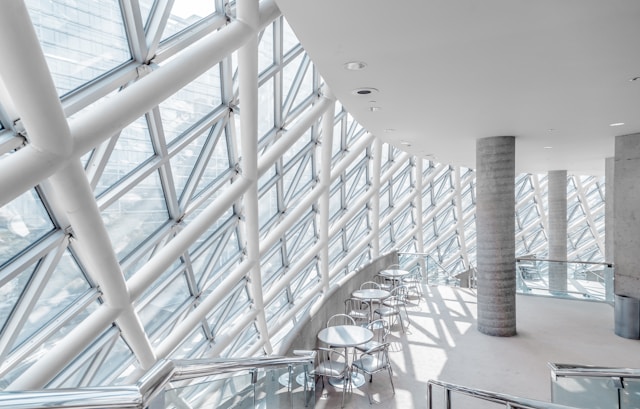 An interior view of a curved glass facade with white criss-cross structural elements in it designed using principles of parametric architecture