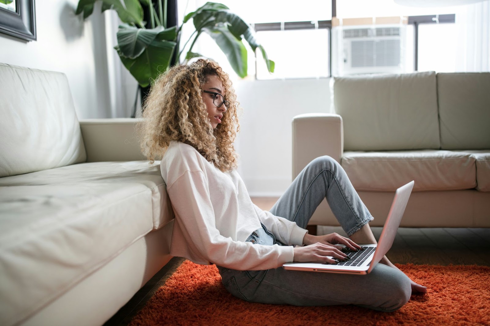 Woman with glasses working from home on an orange carpet