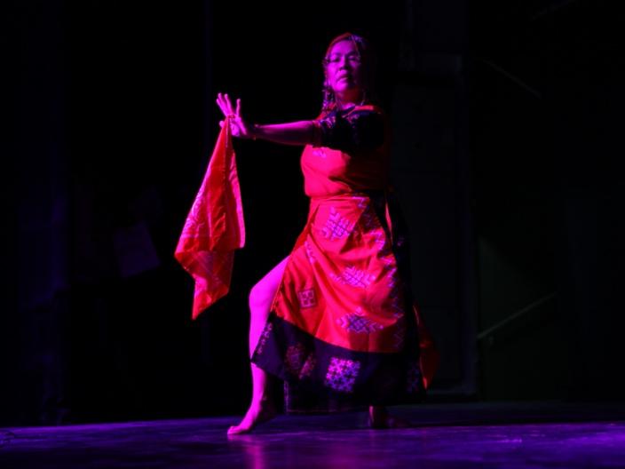 A person in a red dress dancing on a stageDescription automatically generated