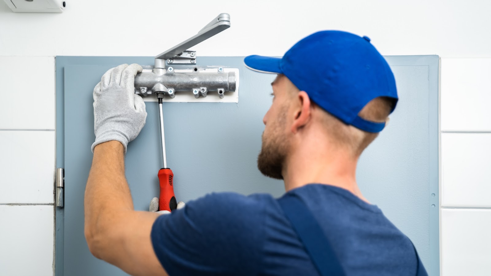 A locksmith installs an automatic door closer on a door, ensuring smooth and controlled door movements.