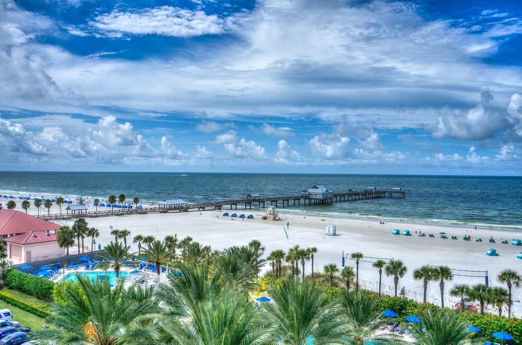 Blue water, white sands, palm trees and a bridge on the shore in the best beaches in the US.