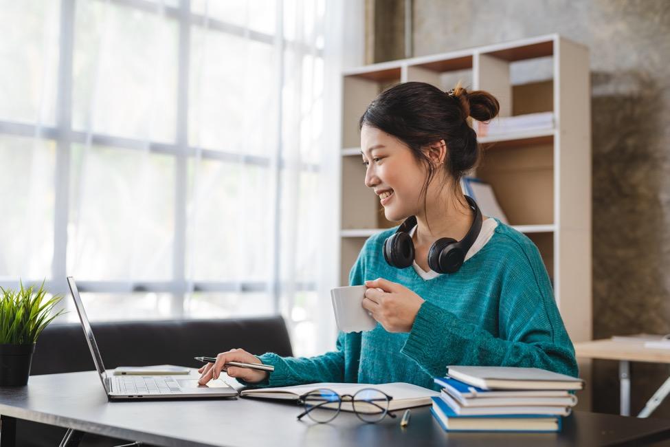 A person sitting at a desk with a computer and a cup of coffeeDescription automatically generated