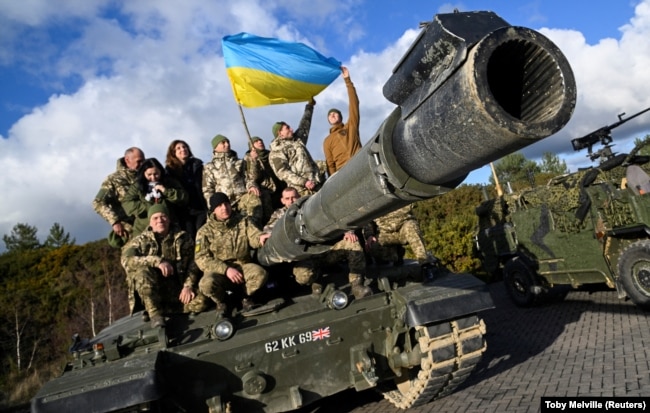 Українські військовослужбовці позують на танку Challenger 2 на військовій базі Bovington Camp на південному заході Великої Британії, де проходять навчання, 22 лютого 2023 року