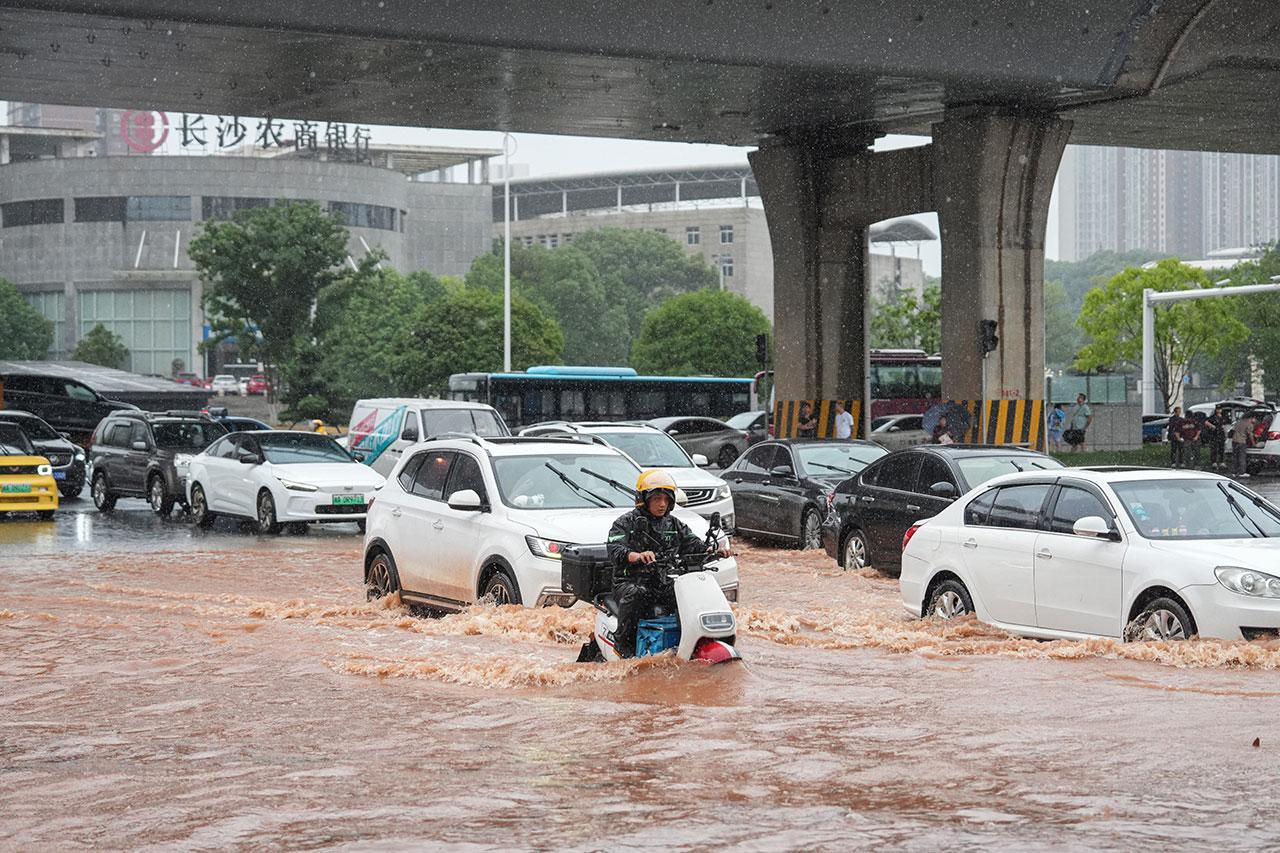 2024年6月24日，汽车驶过被洪水淹没的湖南长沙街道。（法新社）
