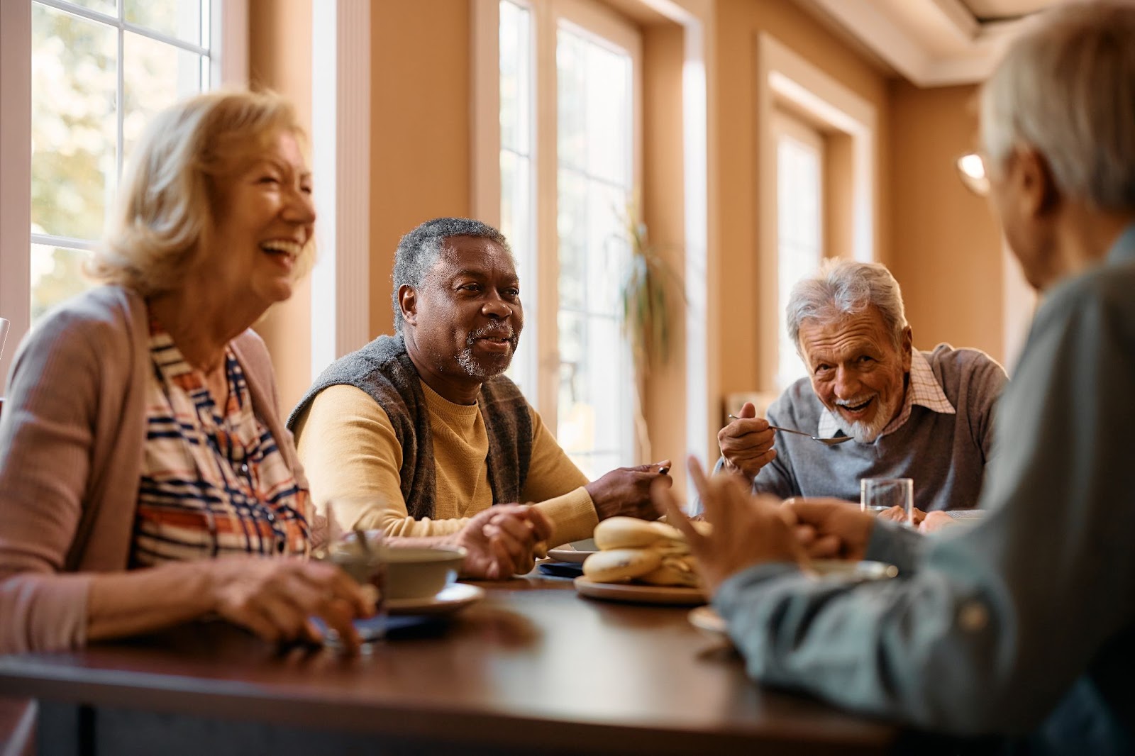 A group of seniors in independent living smiling while eating a meal together.