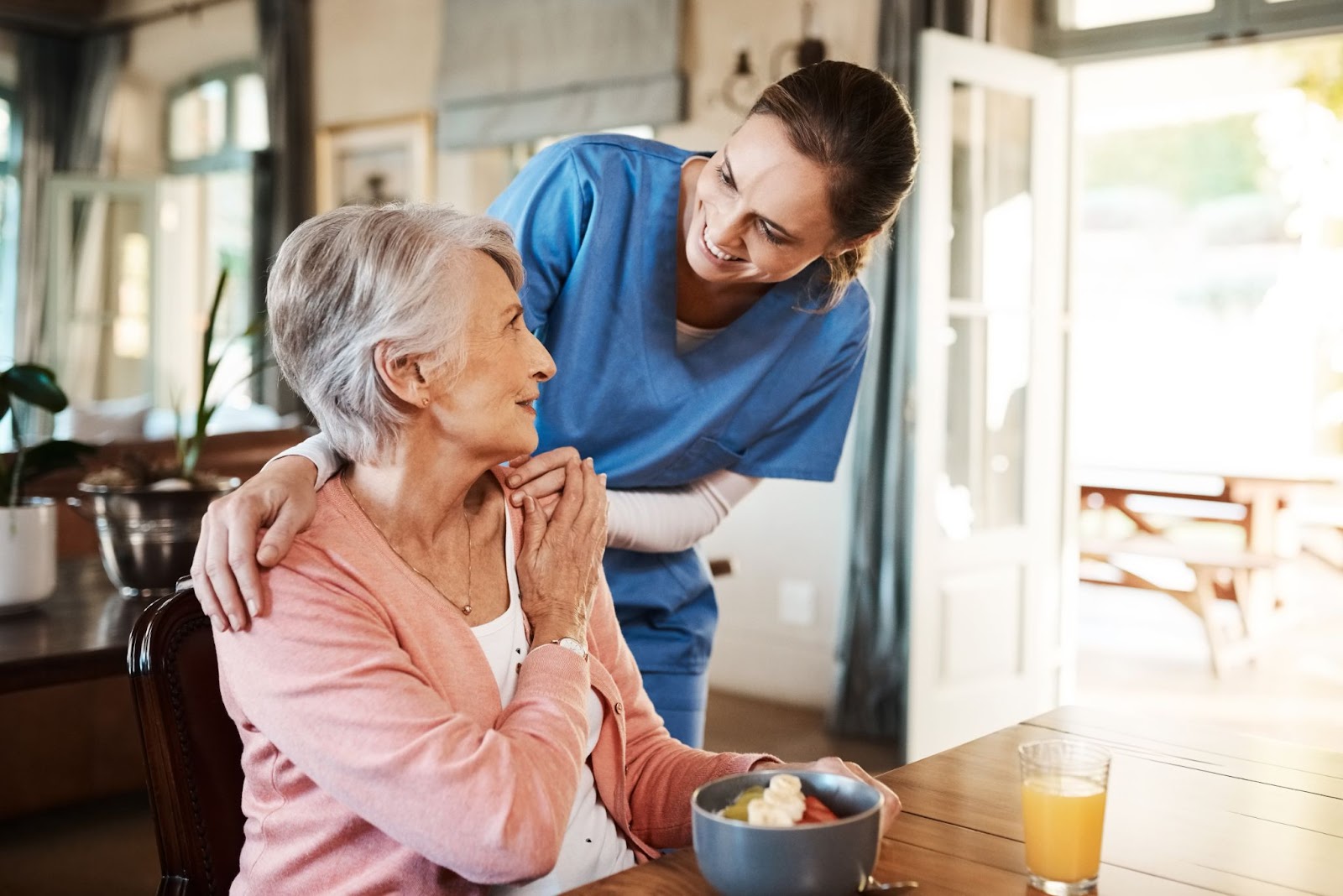 Assisted living caregiving staff smiling and engaging with an elderly woman