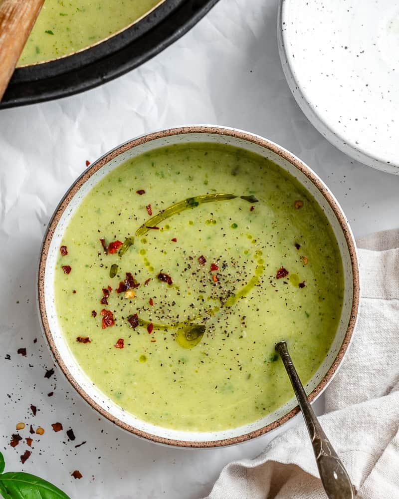 a bowl of vegan zucchini soup in a white bowl.