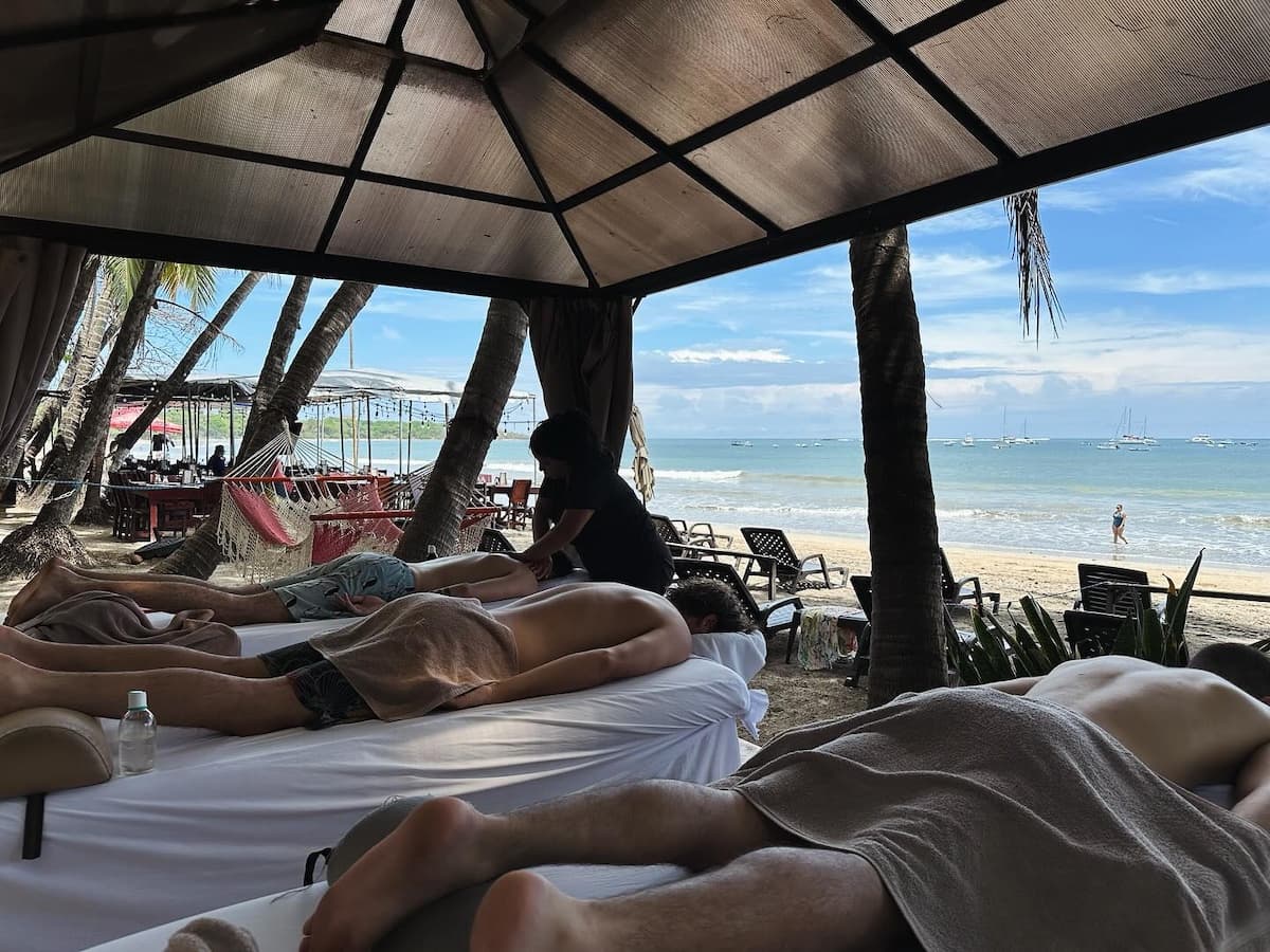 Outdoor spa setup on Tamarindo Beach with three people getting massages with the ocean in the background