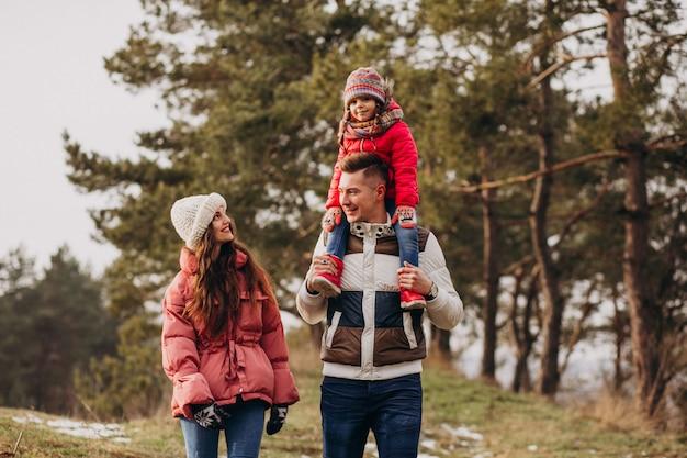 Young family together walking in forest at winter time