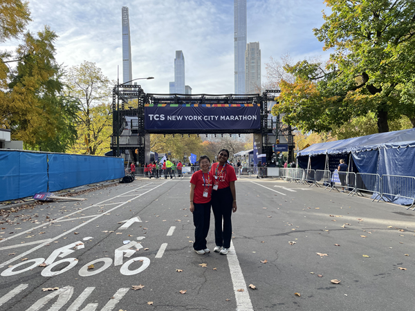two girls in front of the NYC marathon finish line with the NYC skyline in the background