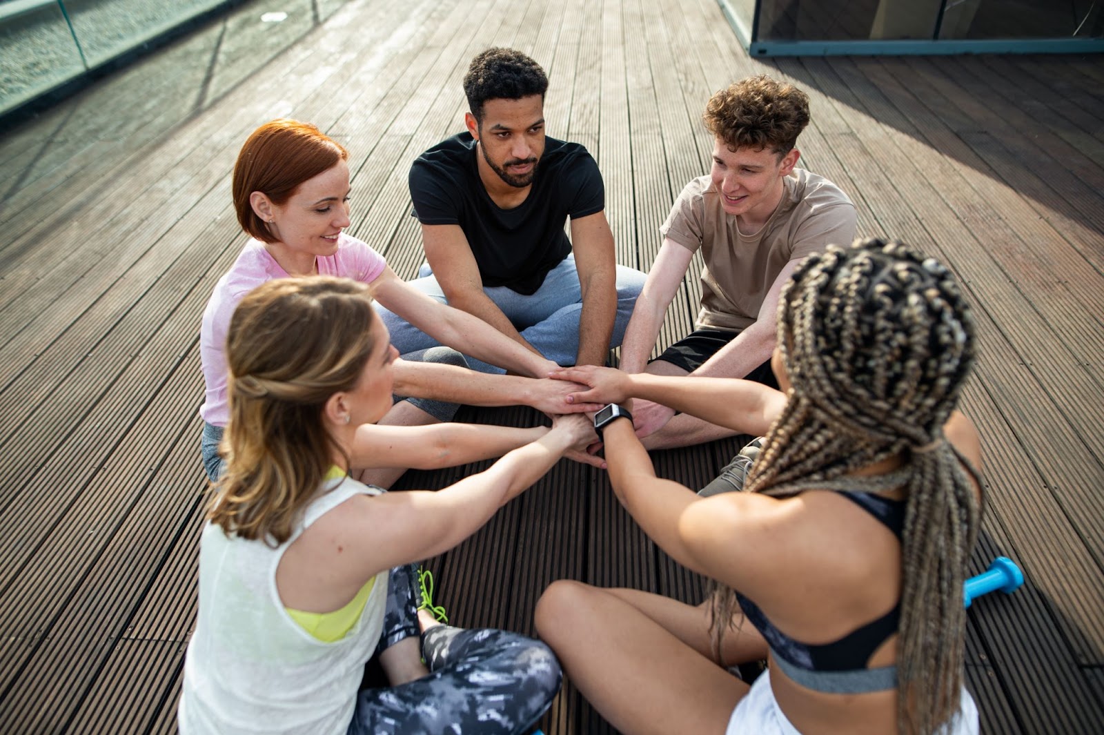 Group of young people with their hands interlaced in the center.