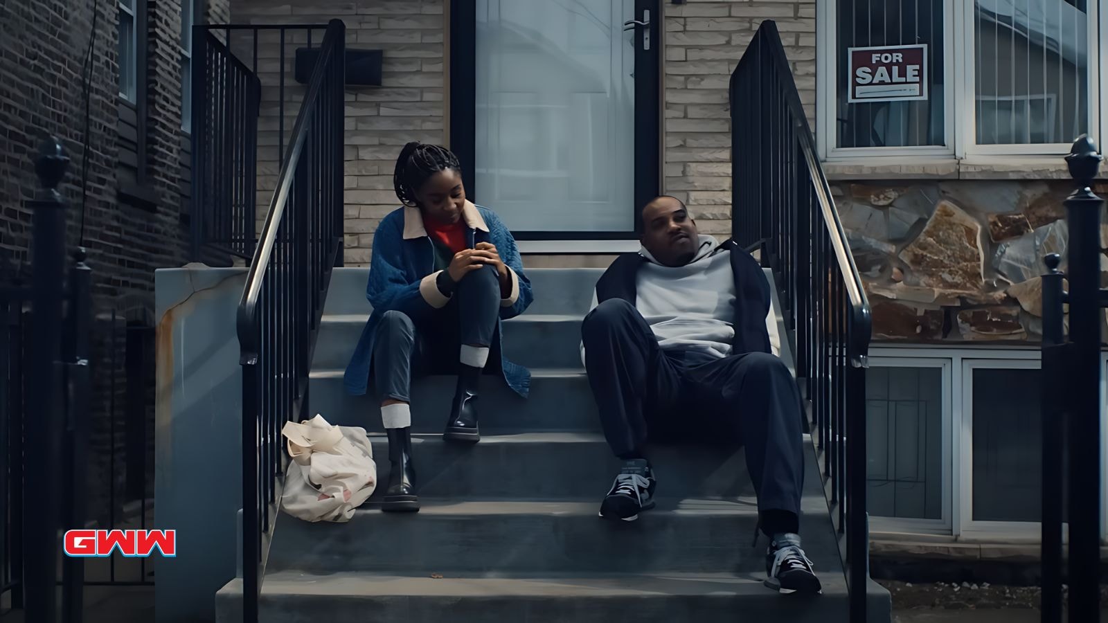 Sydney and Marcus sitting on front steps of a house, deep in conversation.