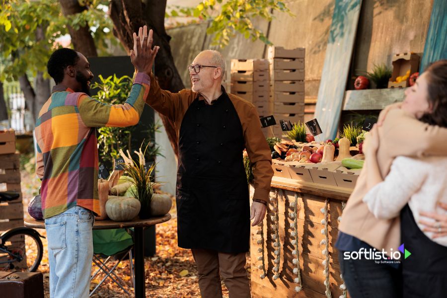 Two men high-fiving at an outdoor market.