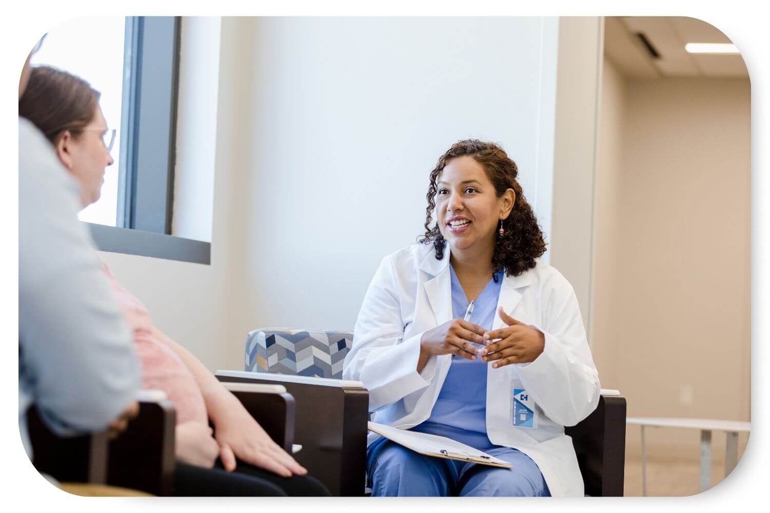 A female medical provider is in discussion with a pregnant patient