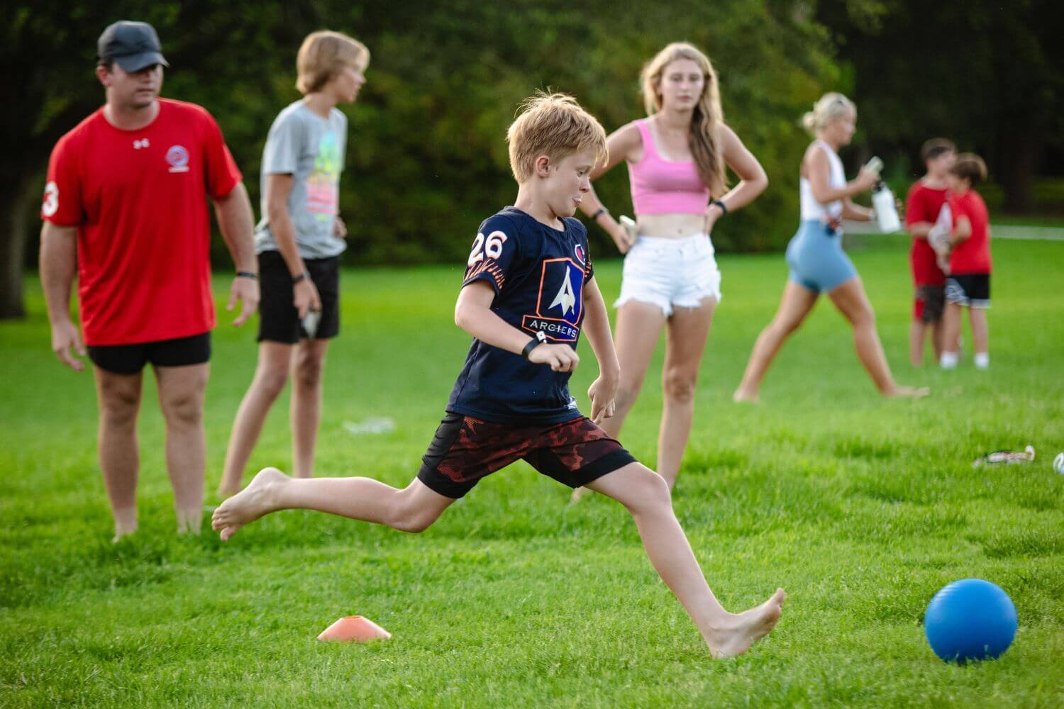 Kids at overnight sports camp playing a game of kickball in a field